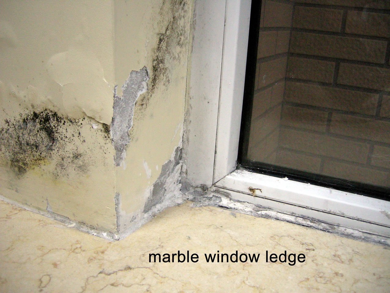 Mold and plaster damage around the left concrete column. Interior is to the left, exterior to the right. The plaster is about 2MM thick and applied directly to the concrete, with a latex interior paint double coat. I don't know what exact material was used to seal the window in place.